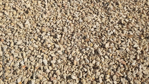 Small gray colour rocks, pebbles, stones or crushed granite gravels on ground seamless background texture. Close up aerial top view.