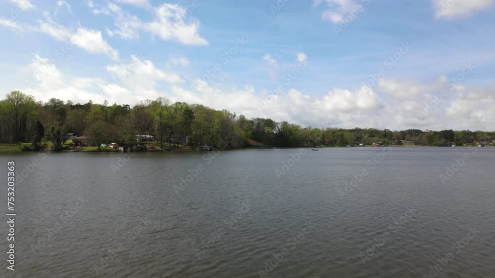 Drone flying above the lake water surface in the countryside, rural place with houses and boat docks for weekend relaxation Drone flying above the lake water surface in the countryside, rural place with houses and boat docks for weekend relaxation