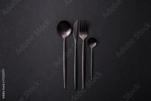 Cutlery fork, knife and spoon on a dark textured concrete background