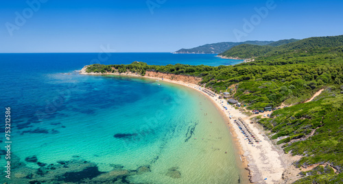 Aerial view of Mantraki beach with emerald sea and lush pine tree forrest at the island of Skiathos, Sporades, Greece