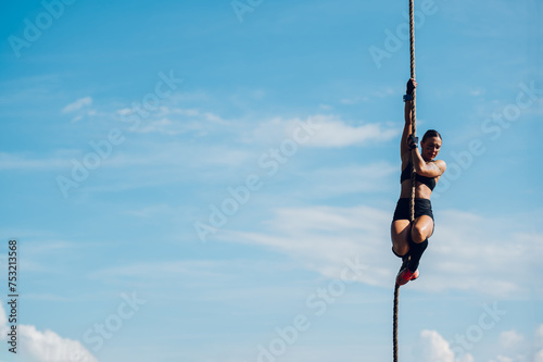 Female partake in an obstacle course race while preparing to climb the rope