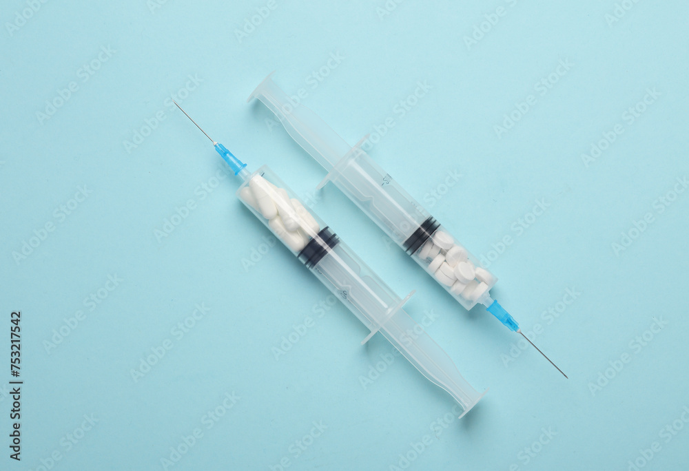 Syringes with pills inside on blue background. Medicine concept Syringes with pills inside on blue background. Medicine concept