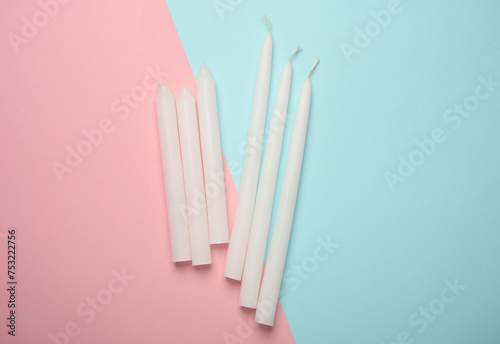 White wax candles on pink blue pastel background