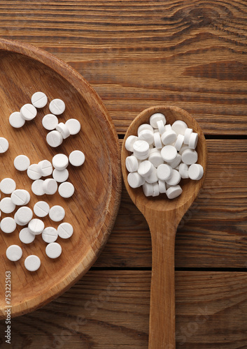 White pills with wooden plate and spoon on table. Top view