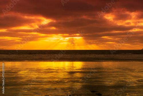 Le soleil décline sur une plage de la Presqu'île de Crozon en Bretagne, peignant le ciel et la mer d'une palette de couleurs envoûtantes, offrant un spectacle sublime et apaisant.