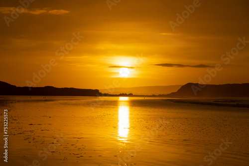 Le soleil se reflète sur le sable mouillé, lui conférant des teintes dorées et orangées, une vision enchanteresse sur la Presqu'île de Crozon en Bretagne. photo