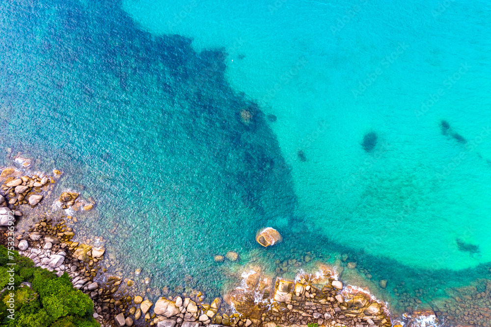 Obraz premium aerial view waves crashing on the rock beside the beach..white bubble waves in turquoise sea on the rock. .creative nature and travel concept.