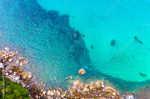 aerial view waves crashing on the rock beside the beach..white bubble waves in turquoise sea on the rock. .creative nature and travel concept.