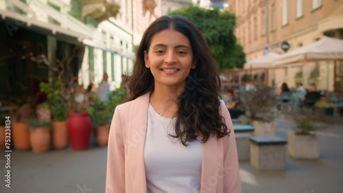 Close up portrait smiling calm young Indian Arabian ethnic woman female girl student businesswoman standing city street cafe outside slowly opening eyes friendly wide toothy healthy smile dental care