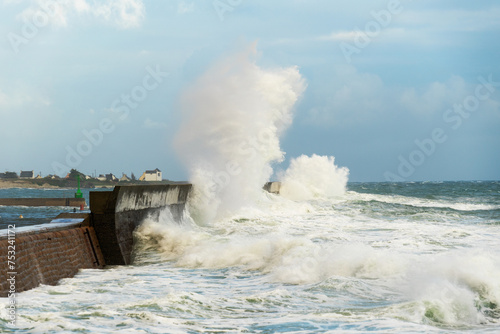 Sous l'emprise de la grande marée, les vagues titanesques s'éclatent contre la jetée de Lesconil, démontrant la force indomptable de l'océan en Bretagne.