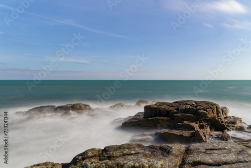 L'effet de pose longue capture la magie de la côte du Finistère sud en Bretagne, figeant le mouvement des vagues dans une symphonie hypnotique de calme et de puissance.