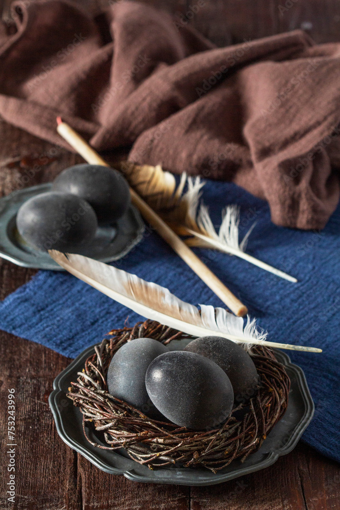 Wine painted eggs in a nest, bird feathers, drapery on a wooden background. Easter concept.
