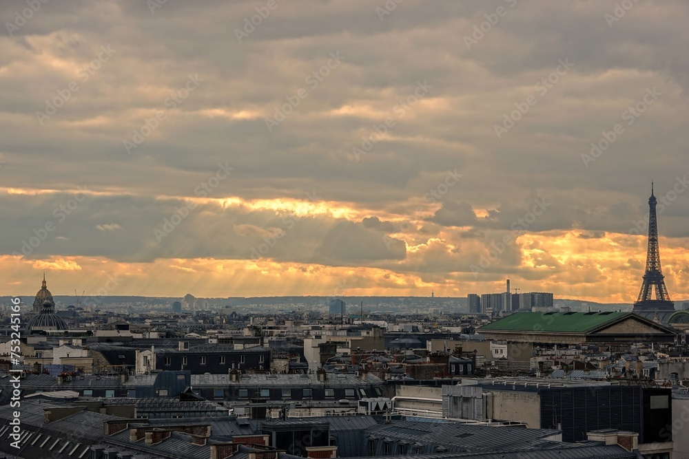 Vue panoramique sur le ciel de Paris en hauteur et rayons du soleil traversant les nuages, avec effet d'accentuation de lumière chaude