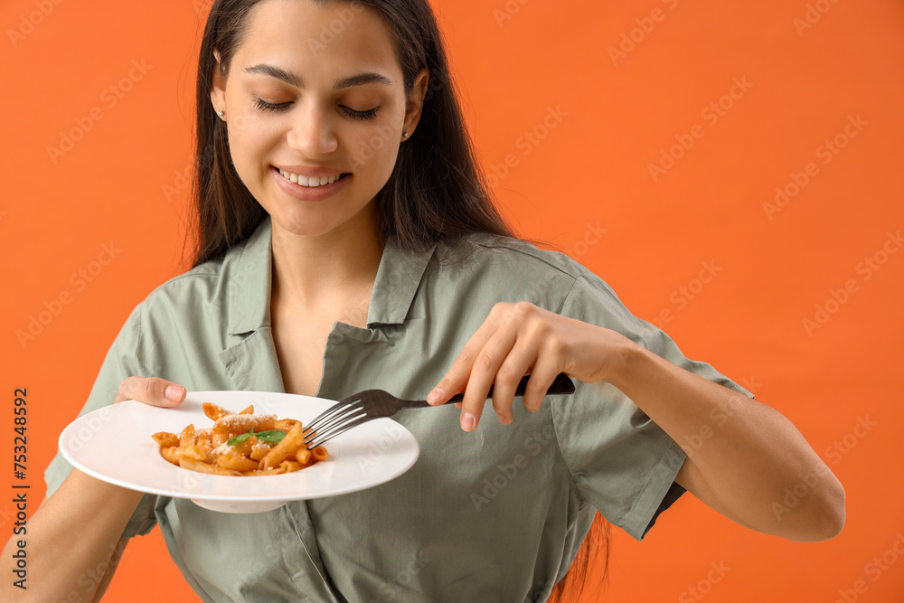 Young woman with tasty pasta on orange background Young woman with tasty pasta on orange background