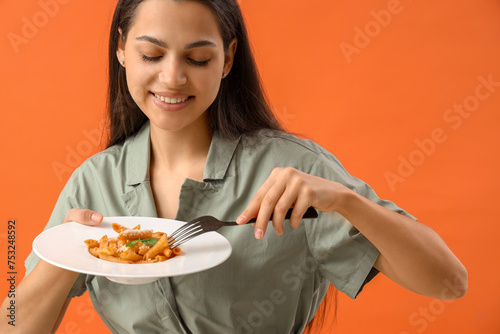 Young woman with tasty pasta on orange background