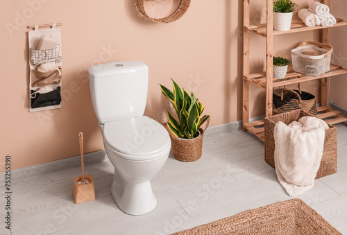 Interior of stylish bathroom with houseplant and ceramic toilet bowl near beige wall © Pixel-Shot