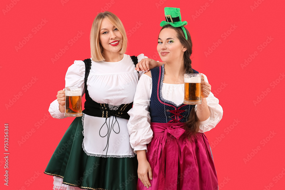 Happy women with beer celebrating St. Patrick's Day on red background Happy women with beer celebrating St. Patrick's Day on red background