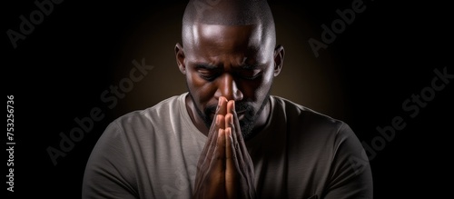 Reflective man with hands clasped kneeling in prayer deep in meditation