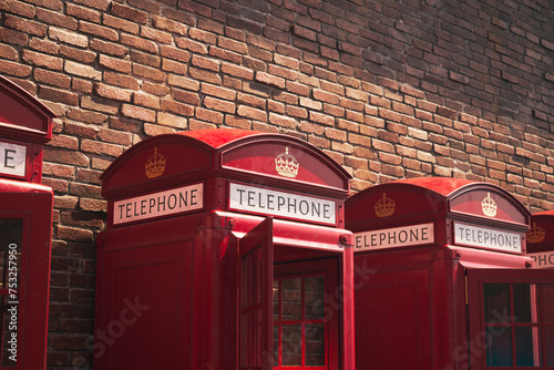 Quintessential Row of British Red Telephone Boxes by Brick Wall FaÃ§ade photo