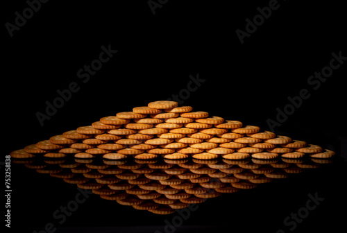 crackers stacked in the shape of a triangle with black background reflect