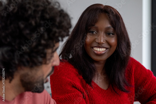 This photograph captures an African American woman with a radiant smile, seemingly engaged in an enjoyable conversation. Her warm, genuine smile and direct eye contact suggest she's deeply connected