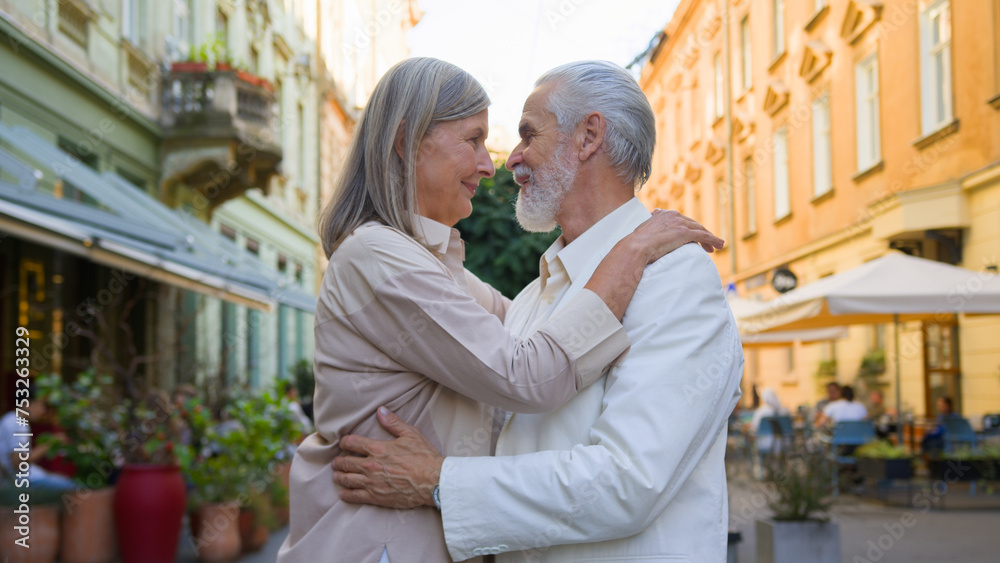 Dreamy senior Caucasian adult mature gray-haired couple woman man looking camera smiling hugging bonding cuddle thinking good future outside. Medicine health care retirement marriage holidays travel