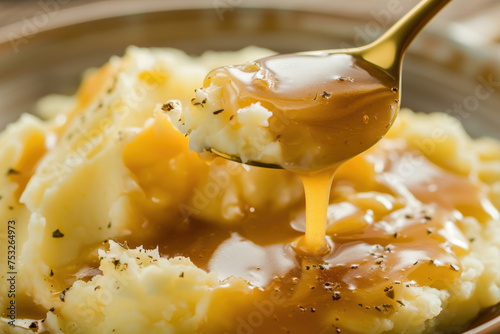 A bowl and spoon of mashed potatoes and gravy. photo