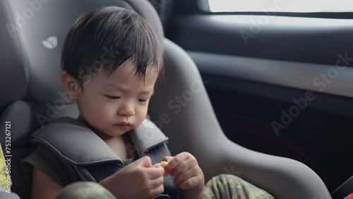 Happy Asian Chinese age 1-2 years old kid enjoying his food while sitting on safety car seat  