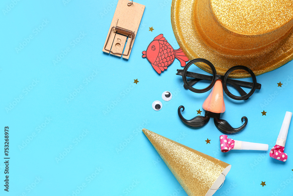 Funny glasses with paper fish, mousetrap and party decor on blue background. April Fools Day - obrazy, fototapety, plakaty 