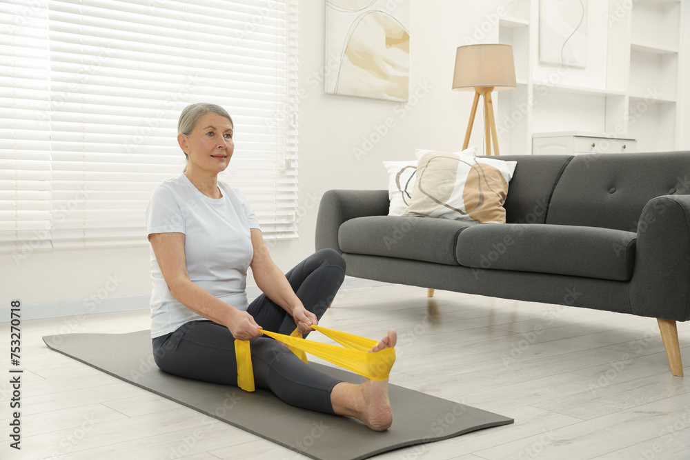 Senior woman doing exercise with fitness elastic band on mat at home Senior woman doing exercise with fitness elastic band on mat at home