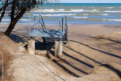 Pre-fabricated beach steps not connected to land because of beach erosion with Lake Michigan in the background.