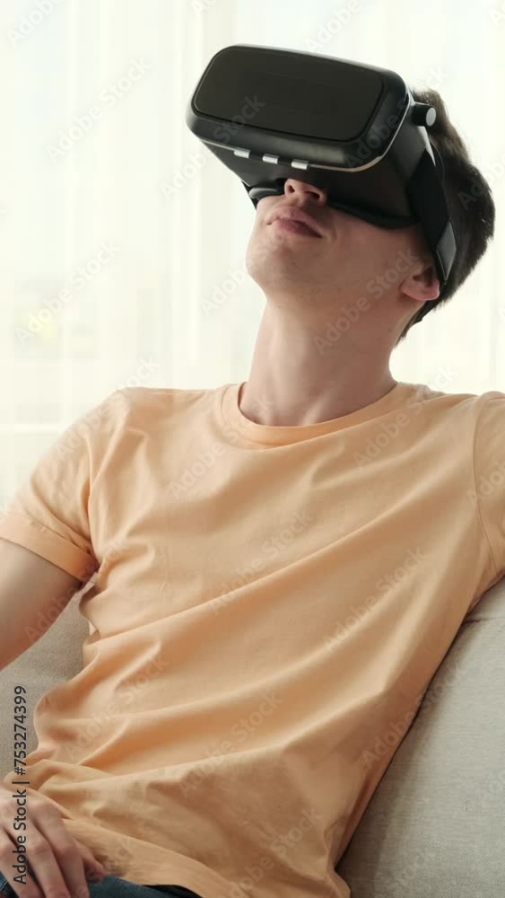 Man exploring new dimensions from the comfort of his home. With a VR headset donned and a sense of anticipation in his eyes, this young man embarks on a thrilling journey of virtual exploration.