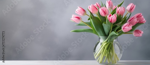Bouquet of pink tulips in glass vase on table with gray background ideal for Easter Women s Day birthday or as a gift for a woman Spring and festive flower arrangement from a florist photo