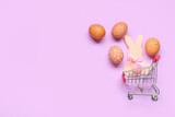Small shopping cart with Easter eggs and bunny on lilac background