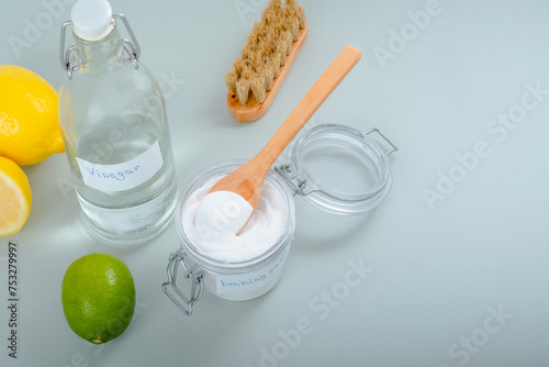 Natural household cleaning products baking soda, white vinegar, citrus fruit, brush on a gray background.
