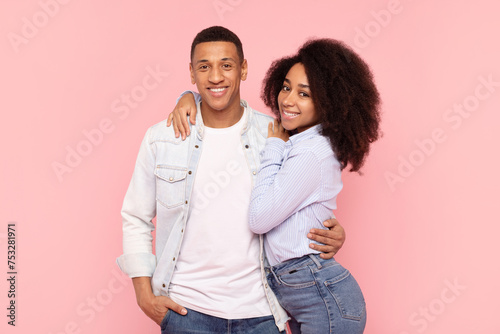 Portrait of black romantic couple embracing while posing over pink studio background, young man and woman hugging and smiling at camera © Home-stock