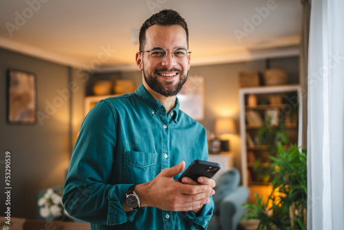One man with eyeglasses stand at home use mobile phone sms texting