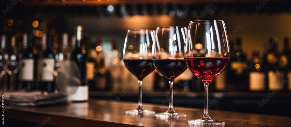 Red wine in glasses next to alcohol bottles on the bar - obrazy, fototapety, plakaty 