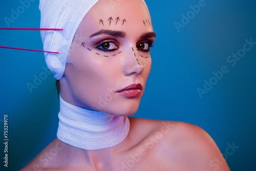 Photo of attractive girl in medical bandage having tape lifting facial procedure over blue color background photo