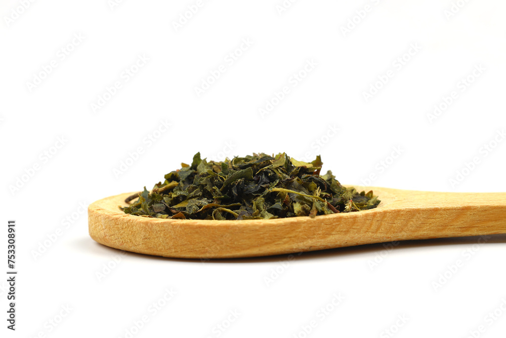 Green tea with herbs in wooden spoons on a White Background. Green tea with herbs in wooden spoons on a White Background.