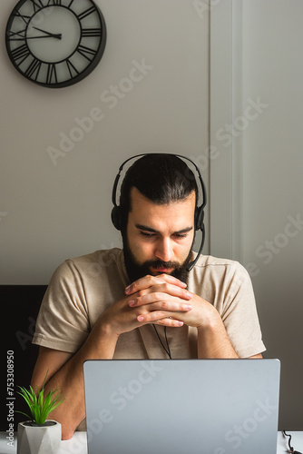 Hotline operator. Portrait of a customer support manager wearing a headset, working with a laptop computer in a home office. Call center worker consulting clients, sitting at desk and smiling.