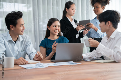 Multiracial analyst team use BI dashboard data to analyze financial report on meeting table. Group of diverse business people utilize data analysis by FIntech for success business marketing. Concord