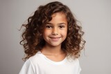 Portrait of a cute little girl with curly hair over gray background