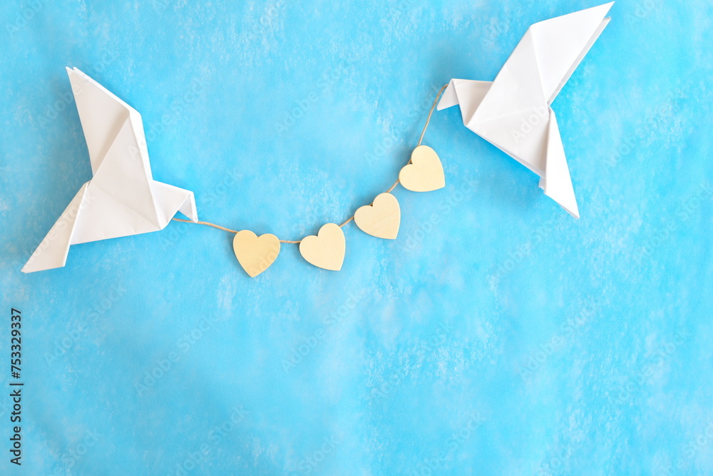 Message of love and kindness. Two white dove origami carrying heart shape on blue background.