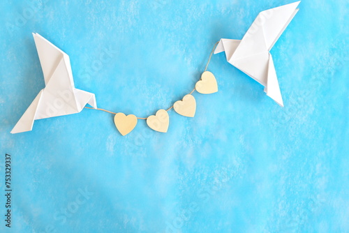 Message of love and kindness. Two white dove origami carrying heart shape on blue background.