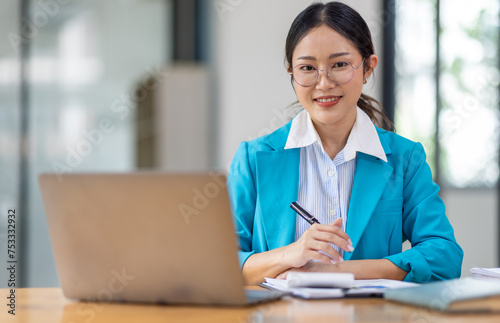 Portrait of asian young female entrepreneur sitting at her desk in the office © David