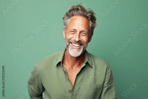 Handsome mature man smiling and looking at camera against green background