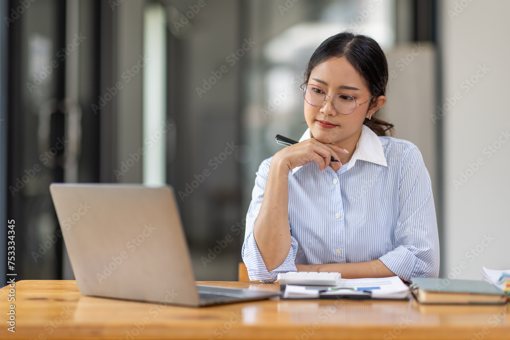 Asian Businesswoman Using laptop computer and working at office with calculator document on desk, doing planning analyzing the financial report, business plan investment, finance analysis concept.
Asian Businesswoman Using laptop computer and working at office with calculator document on desk, doing planning analyzing the financial report, business plan investment, finance analysis concept.