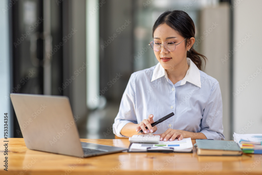 Asian Businesswoman Using laptop computer and working at office with calculator document on desk, doing planning analyzing the financial report, business plan investment, finance analysis concept.
Asian Businesswoman Using laptop computer and working at office with calculator document on desk, doing planning analyzing the financial report, business plan investment, finance analysis concept.