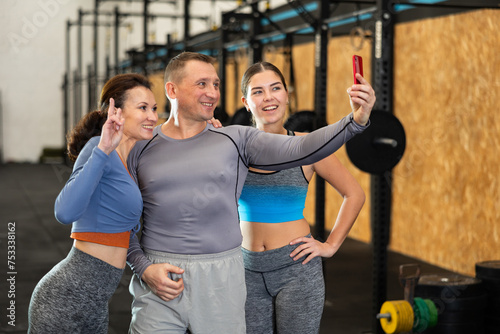 Satisfied athletes taking selfie during training in fitness center